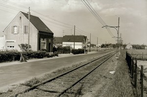 Die Opladener Straße, links mehrere Häuser, in der Mitte eine schmale Straße, rechts die Bahnstrecke der Straßenbahn