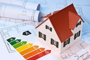 Ein kleines Häusermodell neben einer Karte mit den verschiedenen Energieeffizienzklassen