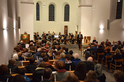 Der Innenraum einer Kirche, alle Bänke sind voll besetzt. Vorne steht Daniel Zimmermann und hält eine Rede