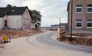 Eine Straßeneinmündung führt vorbei an je einem Gebäude auf der linken und rechten Straßenseite