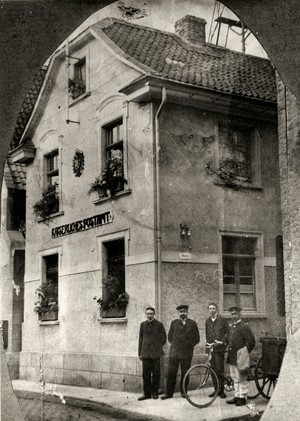 altes schwarz-weiß Foto: das Kaiserliche Postamt am Steinweg, davor vier Männer, einer mit einem Postrad