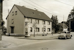 Altes schwarz-weiß Foto: eine Litfaß-Säule an einer Straßenecke vor einem neu gebauten Haus.