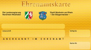 Ein Muster der Ehrenamtskarte: auf gelbem Untergrund die Wappen des Landes NRW und der Stadt Monheim am Rhein, darunter Felder für persönliche Informationen