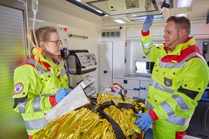 Ein Sanitäter und eine Sanitäterin mit einem Patienten in einem Krankenwagen