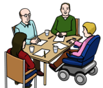Vier Menschen an einem Tisch, davon eine Person in einem elektrischen Rollstuhl
