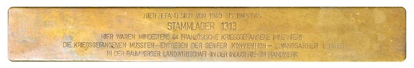 Stolperschwelle mit der Inschrift:Hier befand sich von 1940 bis 1945 das Stammlager 1313. hier waren mindestens 44 französische Kriegsgefangene interniert. Die Kriegsgefangenen mussten - entgegen der Genfer Konvention - Zwangsarbeit leisten in der Baumberger Landwirtschaft - In der Industrie - Im Handwerk