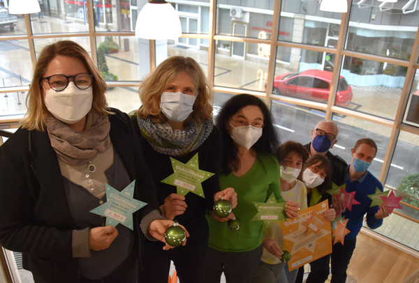 Ursula Blass von der Erziehungsberatungsstelle (v.l.n.r.), Simone Feldmann, Leiterin des Bereichs Kinder, Jugend und Familie, Gerlinde Knisel-Scheuring vom Bereich Kinder, Jugend und Familie, Sabine Schäfer von der Familienhilfe Monheim, Inge Nowak vom Bereich Kinder, Jugend und Familie, Dieter Requadt von der Awo-Suchtberatung und Bürgermeister Daniel Zimmermann präsentieren, gut geschützt mit Mund-Nasen-Bedeckungen, im neuen Mo.Ki-Zentrum die Monheimer Weihnachtssterne und die grünen Weihnachtskugeln, die es bei jedem Kauf dazu gibt. Foto: Birte Hauke