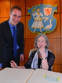 Der Bürgermeister Daniel Zimmermann neben Ulla Hahn. Ulla Hahn hält einen Füller in der Hand und sitzt vor dem goldenen Buch der Stadt