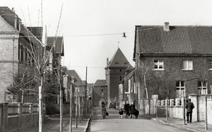 altes schwarz-weiß Bild: Blick in die Alte Schulstraße, am Ende der Straße ist der Schelmenturm, auf der rechten Seite springt ein großes Haus vor, die Katholische Volksschule
