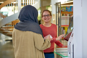 Zwei junge Frauen im Gespräch an der Theke in der Bibliothek