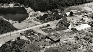 Die Straße „Am Wald“ aus der Luft betrachtet, vermutlich in den frühen 1950er-Jahren. In der rechten Bildhälfte dominiert die Holzhandlung Goebel. Bei dem See handelt es sich um die ehemalige Tongrube, die einst die Ziegelei (am rechten Bildrand) mit Material versorgte. 