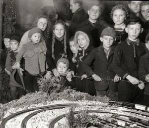 altes schwarz-weiß Bild: viele Kinder unterschiedlichen Altes schauen auf eine große Modelleisenbahnanlage