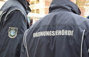 Zwei Personen vom Kommunalen Ordnungsdienst von hinten, auf ihrer Jacke steht: Ordnungsbehörde