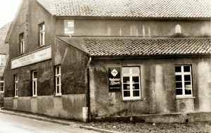 Ein altes schwarz-weiß Foto der Festhalle zur Post. Am Gebäude hängen Werbeschilder, zum Beispiel für das Monheimer Pilsner