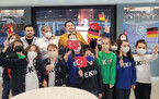 Gruppenfoto von 13 Schülerinnen und Schülern und drei Lehrkräften von der Mittelschule Emlak Konut. Die Schülerinnen und Schüler tragen Mundschutze und winken mit kleinen Deutschlandfahnen und Türkeifahnen.