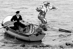 Ein als Spielmann verkleideter Norbert Pergande springt von einem Ruderboot ans Ufer