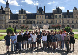 Gruppenfoto von etwa 30 Austauschschülerinnen und Schülern vom Otto-Hahn-Gymnasium vorm Schloss Fontainebleau bei Paris. Das Schloss wurde im Renaissancestil gebaut. Zwei gewundene Treppen führen zum Eingang.