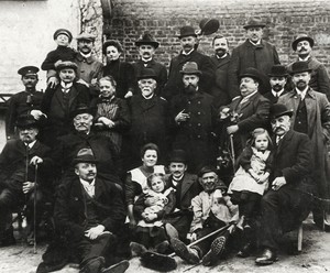 Altes schwarz-weiß Foto: Ein Gruppenfoto mit mehreren Männern in dunklen Anzügen, und mehrerer Frauen