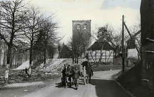 Zwei Männer mit einem vom Pferd gezogenen Planwagen, im Hintergrund der zerstörte Turm der Kirche St. Gereon