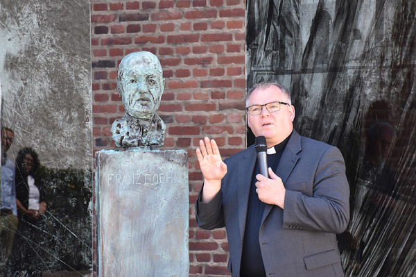 Pfarrer Michael Hoßdorf lädt am Denkmal zum Nachdenken ein: An welcher Stelle kann ich dem Beispiel von Pfarrer Franz Boehm folgen?