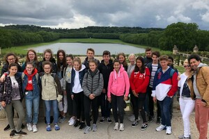 Eine Gruppe Schülerinnen und Schüler auf einer Erhöhung vor einem See, im Hintergrund viele Bäume