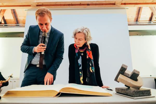 Bürgermeister Daniel Zimmermann und Schriftstellerin Ulla Hahn tragen sich ins Goldene Buch ein. Rechts steht der Wi(e)derworte-Preis. Foto: Tim Kögler