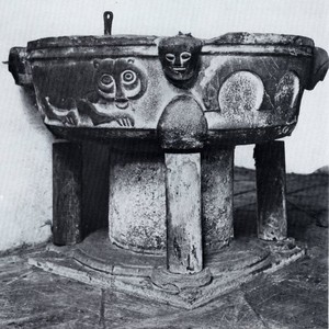 Schwarz-weiß Foto eines Taufsteins mit verschiedenen ausgestalteten Figuren