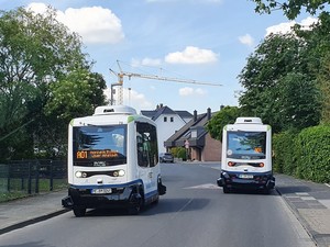 Zwei autonome Busse nebeneinander auf einer Straße