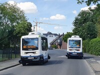 Zwei autonome Busse nebeneinander auf einer Straße