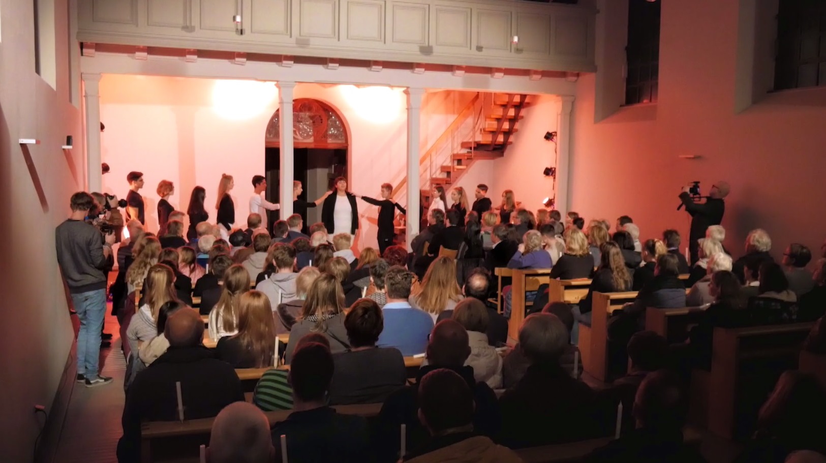 Eine Gruppe Jugendliche führt in einem Kirchenraum vor Publikum ein Theaterstück auf