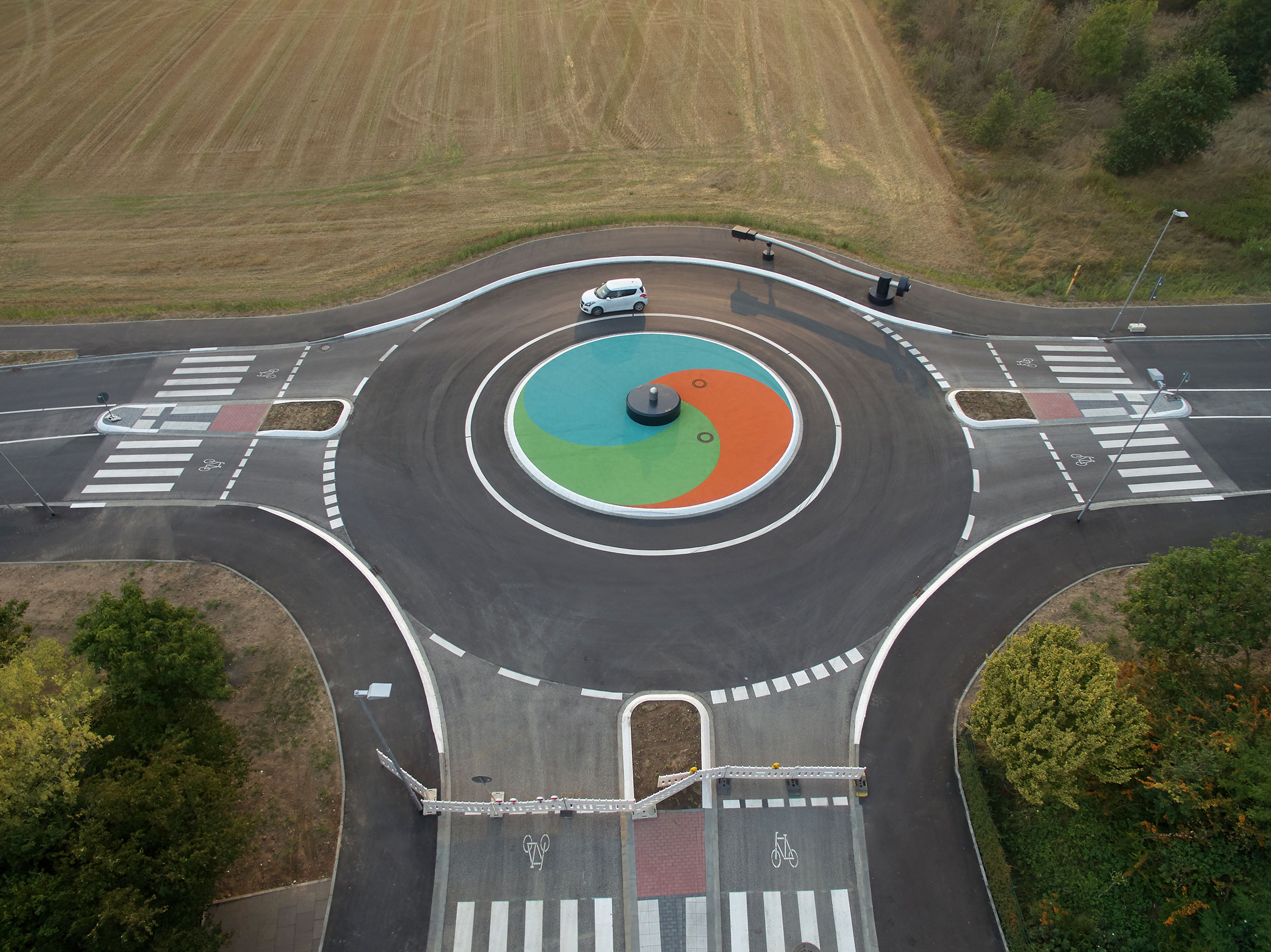 Drohnen-Blick auf den Kreisverkehr mit Kunstwerk beim fließenden Verkehr